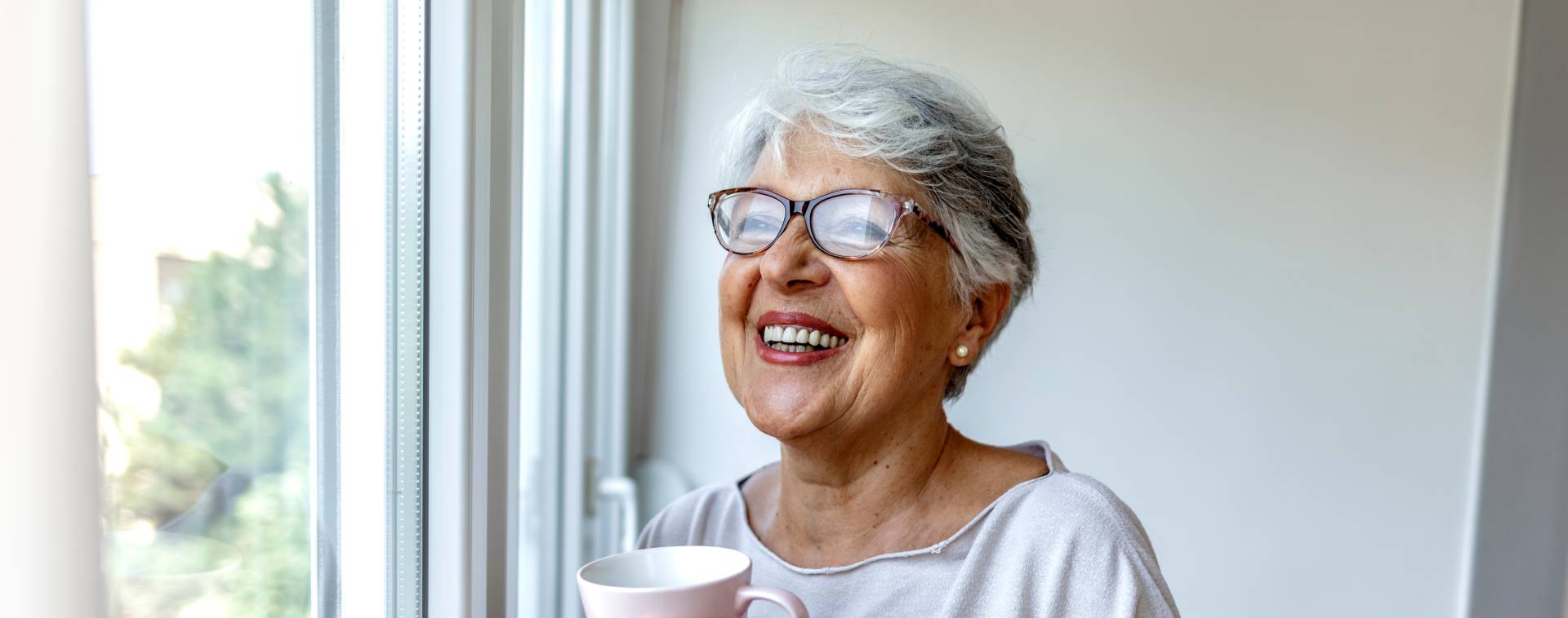 happy senior woman smiling and looking through the window