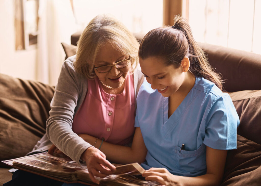 senior looking through a photo album with a healthcare worker