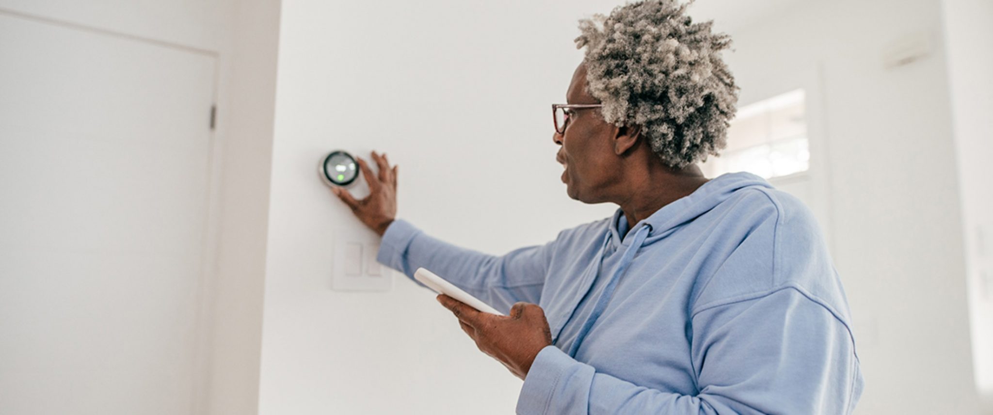 senior changing the temperature on a smart thermostat