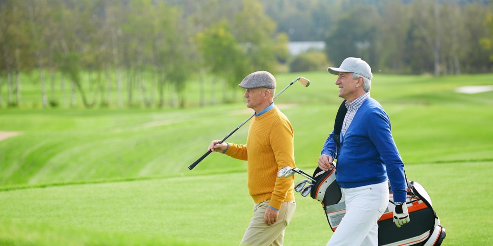 Two senior men walking on a golf course.