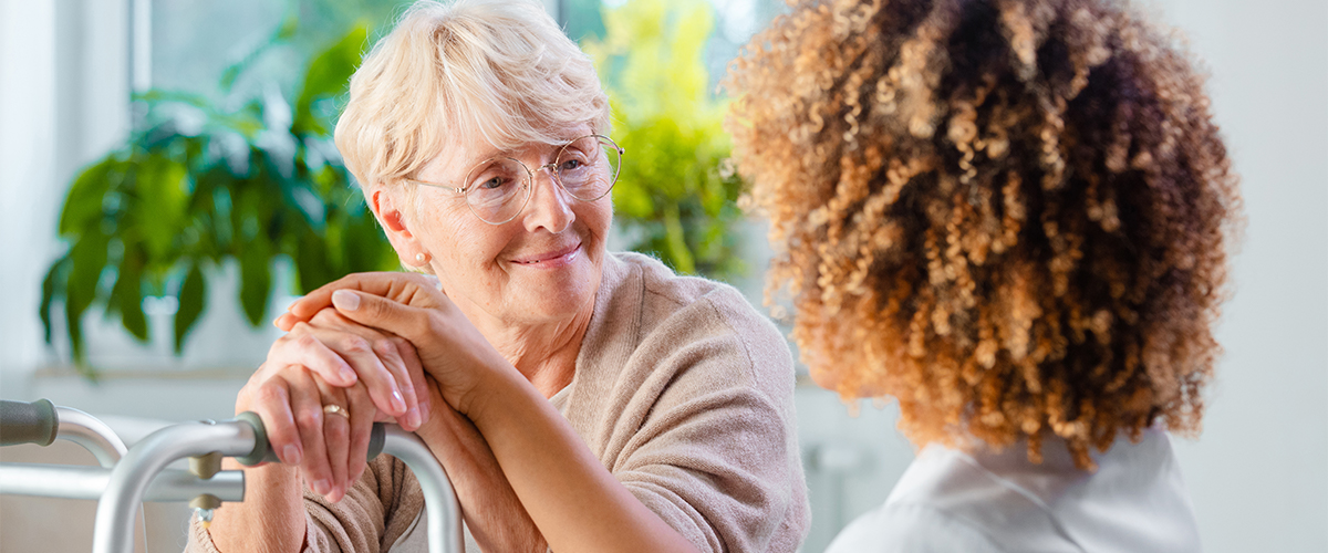 Two senior women sit at the kitchen table and talk