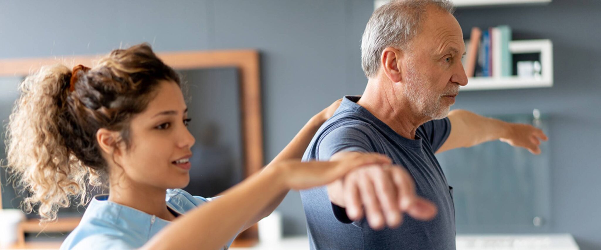 A physical therapist helps a senior man do balance exercises