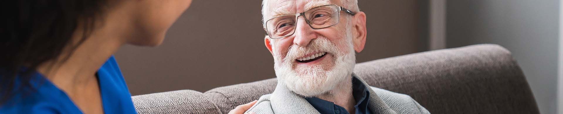 elderly man smiling while talking with a healthcare worker