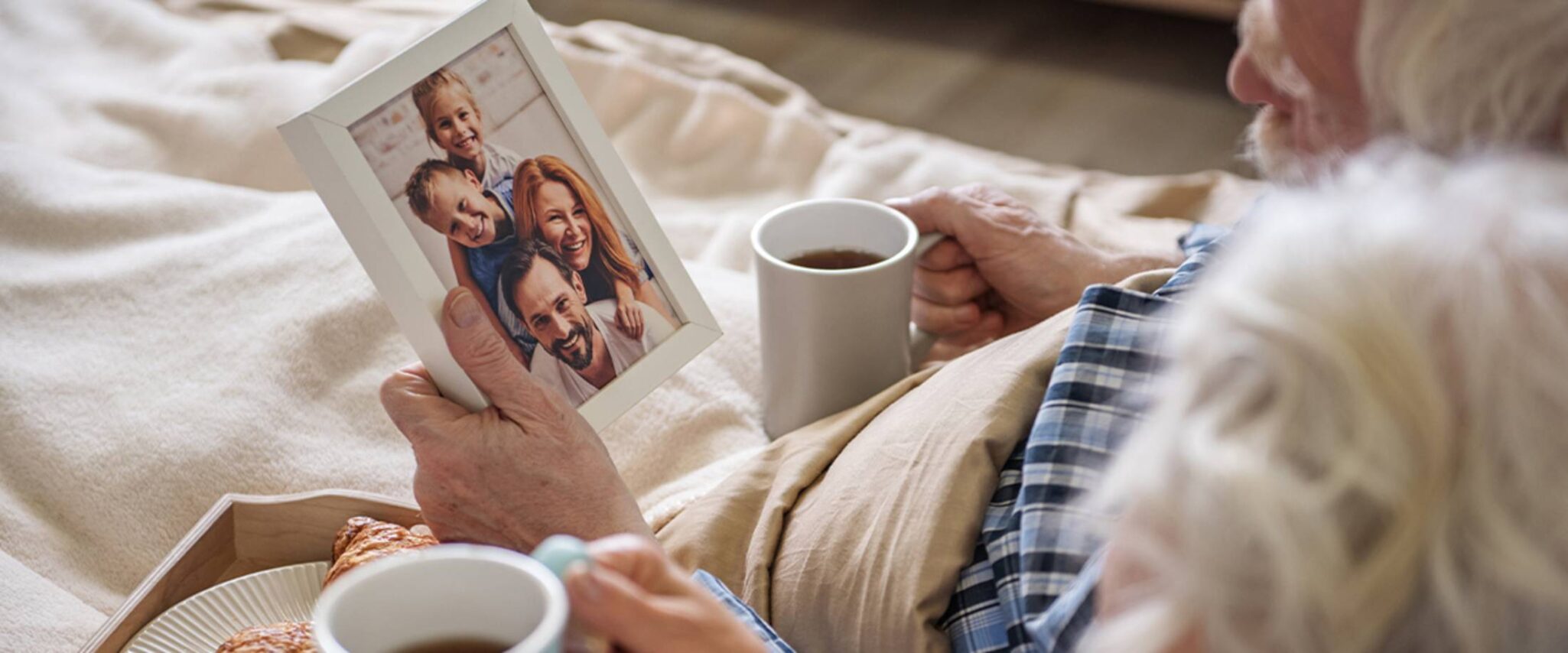 Elderly couple looking at a picture of family while drinking coffee together