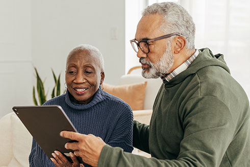 a senior couple look at a tablet together