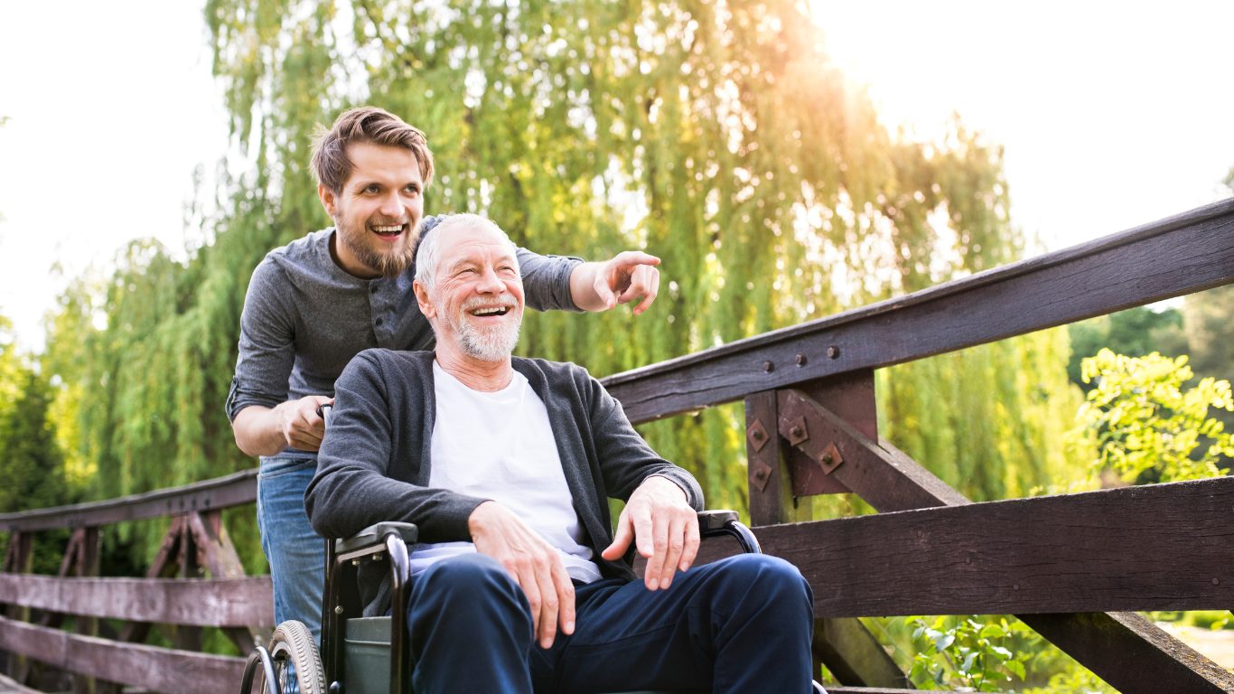 Senior man in wheelchair with adult son on outdoor walk