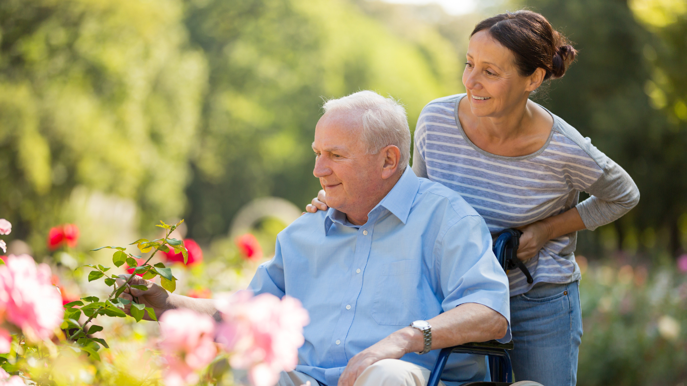 Senior man in wheelchair with caregiver in garden