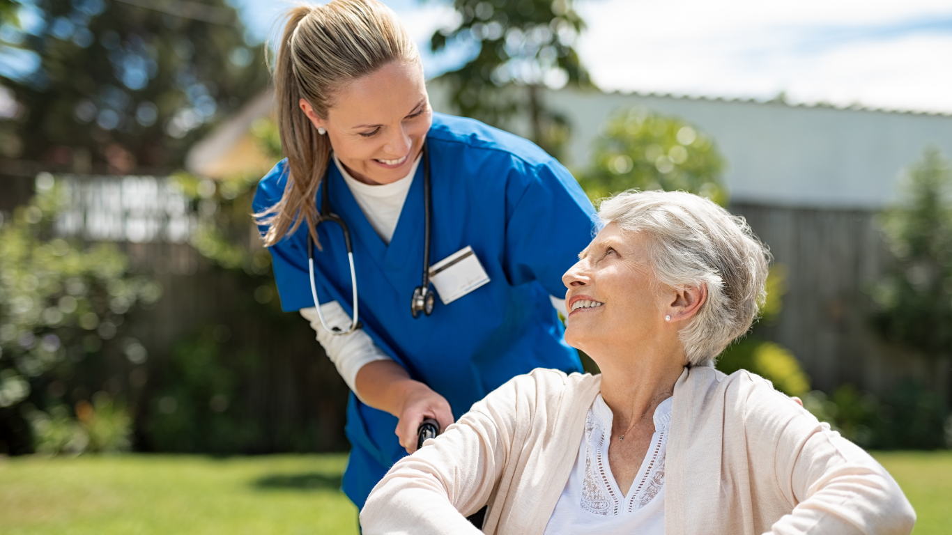 Senior woman in wheelchair smiling at female nurse