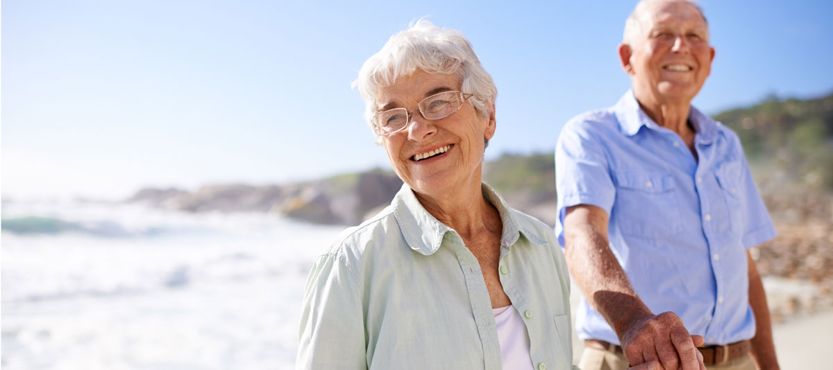 senior woman holds the hand of her husband on the beach