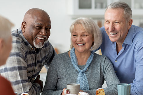 A group of seniors smile and chat over coffee.