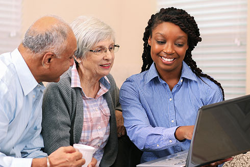 A senior couple looks at a computer with a staff member.