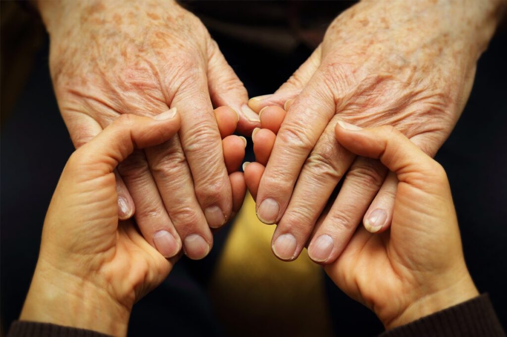 senior hands in a younger person's hands